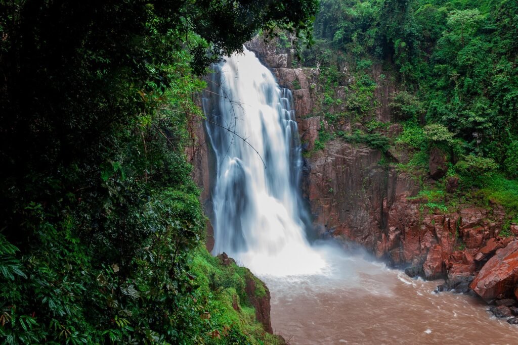 Haew Narok Waterfall in full flow over red rock cliffs in Khao Yai